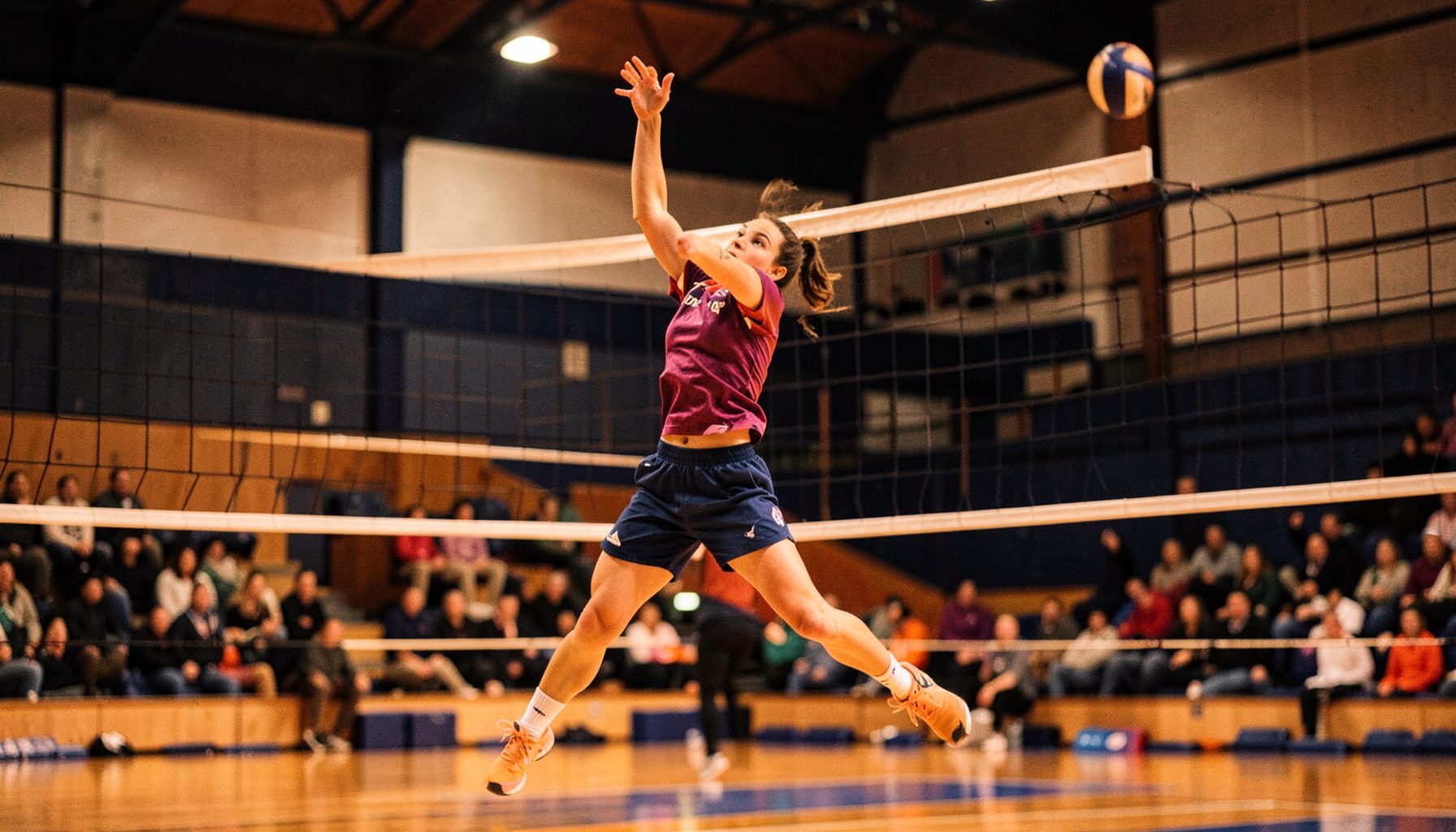 Volleyball player leaping for a spike in an indoor arena, warm amber and navy tones