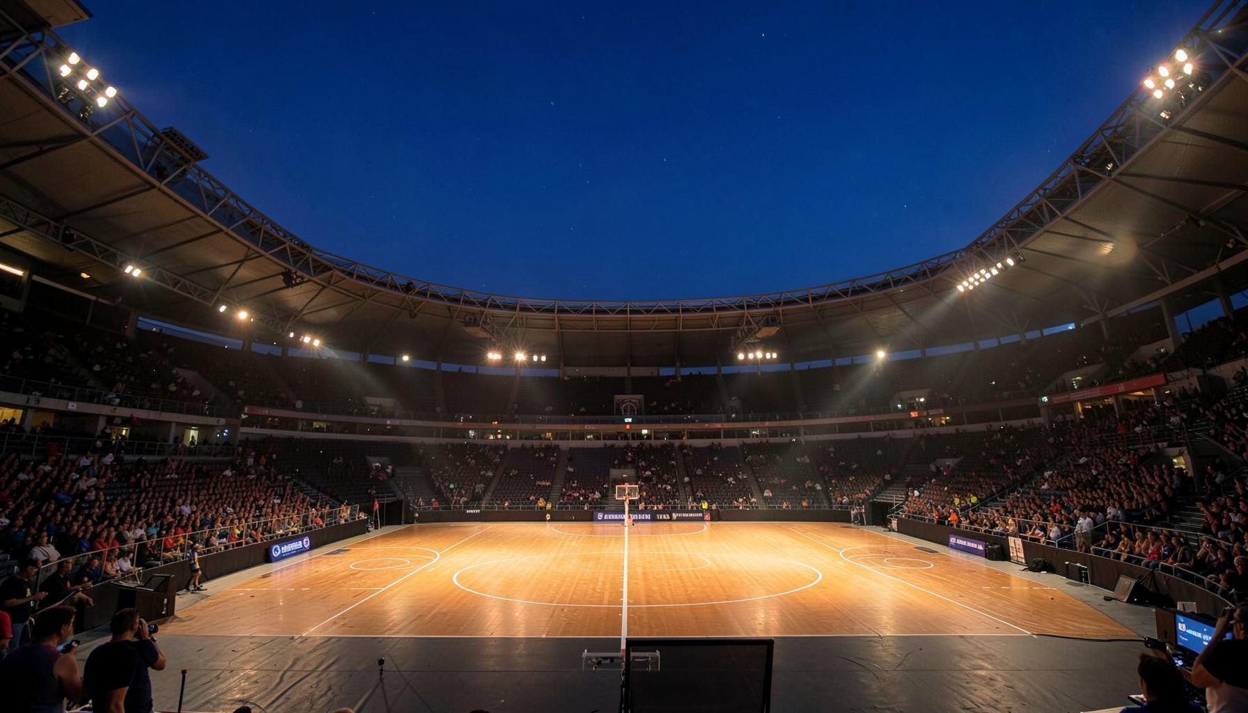 A dramatic sports arena at dusk with floodlights casting a warm glow over the court, deep blue sky above